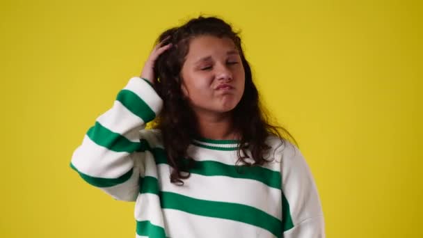 彼女の髪に触れる1人の女の子の4Kビデオと黄色の背景の上に何かについて考えて 感情の概念 — ストック動画