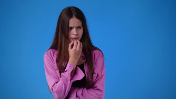 1人の若い女の子の4Kビデオは心配し 青い背景の上に彼の顔に手を置きます 感情の概念 — ストック動画