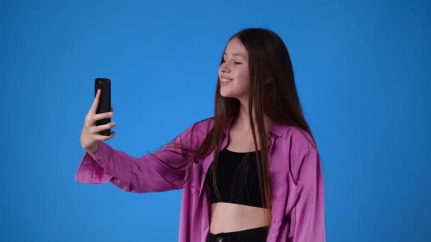 青い背景を持つビデオ通話で誰かと話している1人の少女の4Kビデオ 感情の概念 — ストック動画