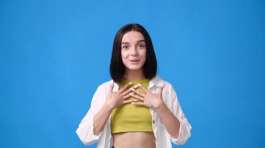 Genç bir kızın 4k videosu mavi arka planda seviniyor. Duyguların kavramı.