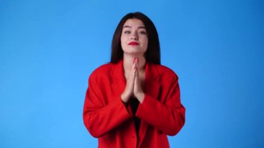 Mavi arka planda tatlı tatlı yalvaran bir kadının 4K videosu. Duyguların kavramı.