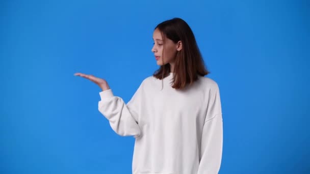 Sağ Elinde Mavi Arka Planda Bir Şey Gösteren Bir Kızın — Stok video
