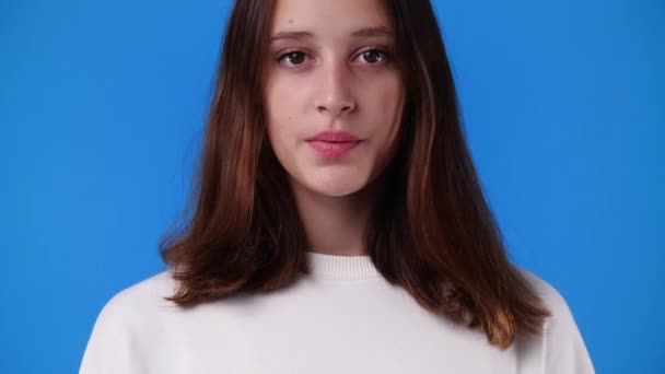 4K视频 一个女孩在蓝色背景下摆出严肃的面孔 情绪的概念 — 图库视频影像