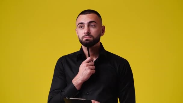 黄色の背景の上にタブレットでペンで何かを考え メモする1人の男の4Kビデオ 感情の概念 — ストック動画