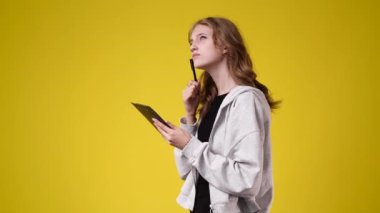 4k video of one girl taking notes over yellow background. Concept of emotions.