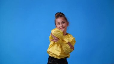 Mavi arka planda poz veren bir kızın 4K videosu. Duyguların kavramı.