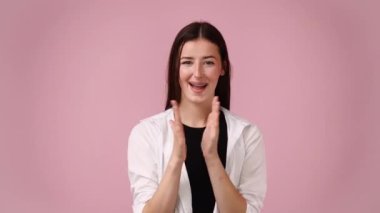 Heyecanlı bir kızın pembe arka planda el çırpışının 4K videosu. El çırpma kavramı.