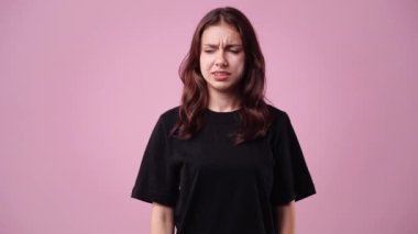 Pembe arka planda alnına dokunan bir kızın 4K videosu. Duyguların kavramı.