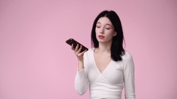 ピンクの背景に携帯電話を使って可愛い女の子の4K動画 感情の概念 — ストック動画