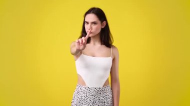 Sarı arka planda dur işareti gösteren bir kızın 4K videosu. Duyguların kavramı.