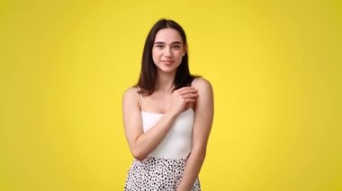 Sarı arka planda poz veren bir kızın 4K videosu. Duyguların kavramı.