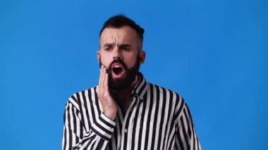 4k video of one man with negative facial expression on blue background. Concept of negative emotion.