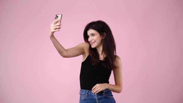 携帯電話で可愛い女の子の4K動画やピンクの背景にこんにちは 感情の概念 — ストック動画