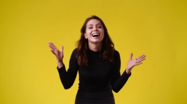 Sarı arka planda poz veren bir kızın 4K videosu. Duyguların kavramı.