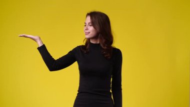 4k video of one girl pointing at left over yellow background. Concept of emotions.