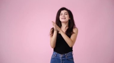 Heyecanlı bir kızın pembe arka planda el çırpışının 4K videosu. El çırpma kavramı.