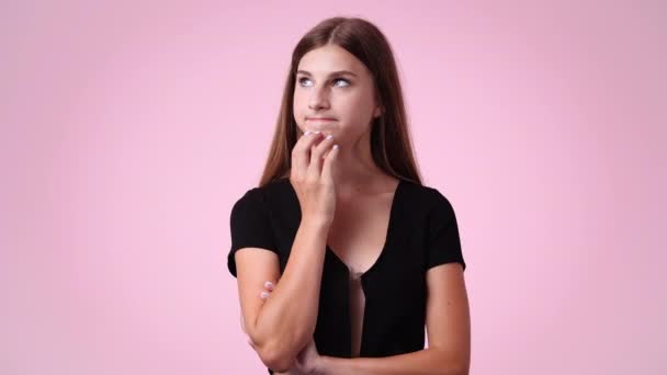 ピンクの背景の上に何かを考えている女性の4Kビデオ 感情の概念 — ストック動画