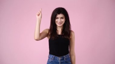 Bir kızın 4K videosu pembe arka plandaki bir şey için çok heyecanlı. Duyguların kavramı.