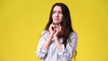 Sarı arka planda başı ağrıyan bir kızın 4K videosu. Duyguların kavramı.