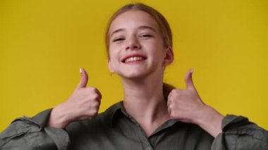 4k video of one girl showing thumbs up over yellow background. Concept of emotions.
