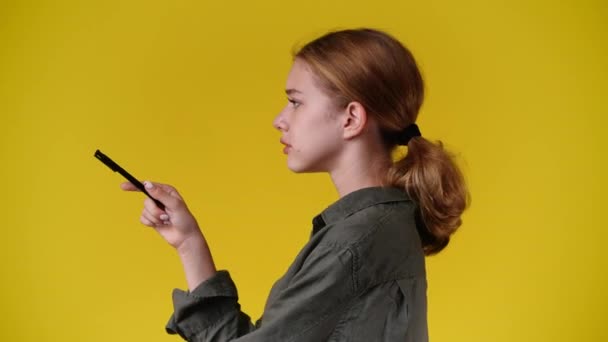 4K视频 一个女孩在黄色的背景上摆出一副视频的姿势 — 图库视频影像