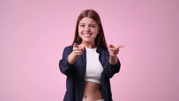 ピンク色の背景に親指を立てて微笑む女の子の4K動画 感情の概念 — ストック動画