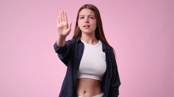 ピンク色の背景の上に何かに立ち止まり否定的に反応する1人の少女の4Kスローモーションビデオ 感情の概念 — ストック動画