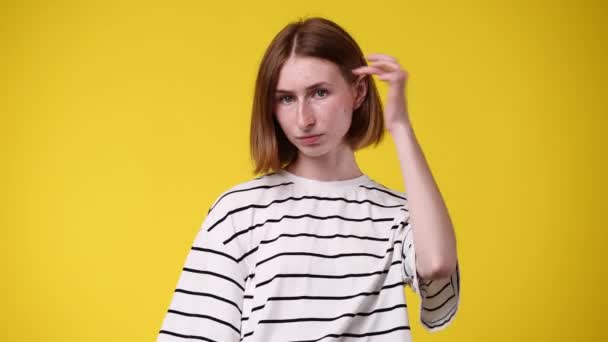 髪を固定し 黄色の背景に笑みを浮かべている1人の女の子の4Kビデオ 感情の概念 — ストック動画