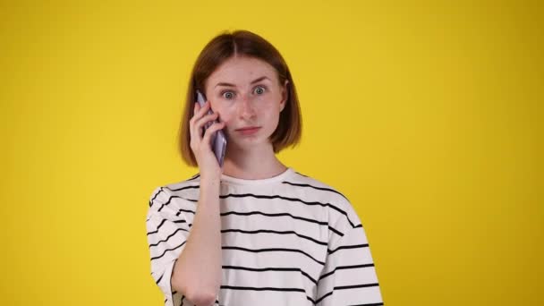 ピンクの背景を持つ誰かと電話で話している否定的な顔の表情を持つ1人の女の子の4Kビデオ 感情の概念 — ストック動画