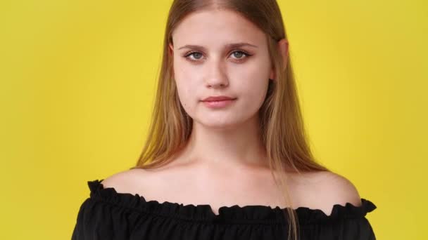 黄色い背景にウィンクする1人の少女の4Kスローモーションビデオ 感情の概念 — ストック動画