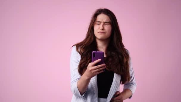 1人の女の子がテキストを入力し ピンクの背景を笑いながら検索する4Kビデオ 感情の概念 — ストック動画
