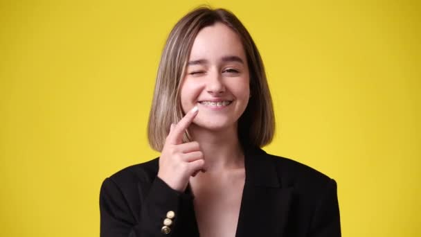 一个女孩的4K视频将他的手指指向支撑 并在黄色背景上微笑 情绪的概念 — 图库视频影像
