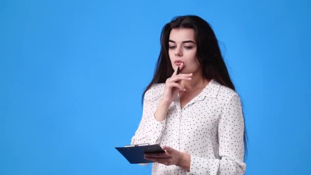 青い背景の上にタブレットでペンで何かを考え メモする1人の少女の4Kビデオ 感情の概念 — ストック動画