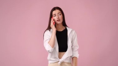 4k video of one girl talking on the phone over pink background. Concept of emotions.