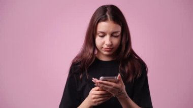 Pembe arka planda duygusal olarak sevinen bir kızın 4k yavaş çekim videosu. Duyguların kavramı.