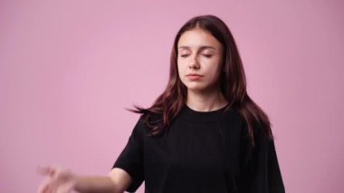 Pembe arka planda facepalm işareti yapan bir kızın 4K videosu. Duyguların kavramı.