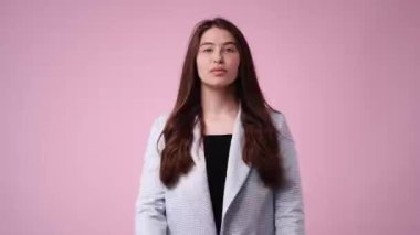 Gülümseyen bir kızın 4K videosu ve pembe arka planda bir öpücük gönderiyor. Duyguların kavramı.
