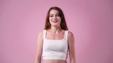 Pembe arka planda oturan bir kızın 4K videosu. Duyguların kavramı.