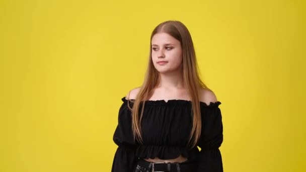4K视频 一个女孩用右手在黄色背景上展示某样东西 情绪的概念 — 图库视频影像