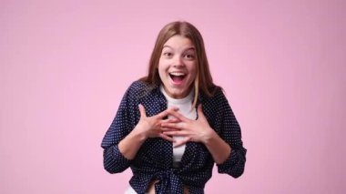Pembe arka planda duygusal olarak sevinen bir kızın 4k yavaş çekim videosu. Duyguların kavramı.