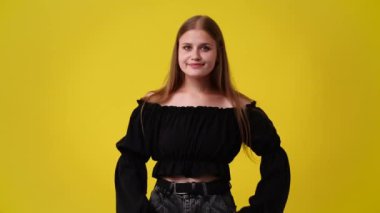 Sarı arka planda aşk belirtisi gösteren bir kızın 4K videosu. Duyguların kavramı.