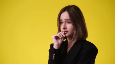 4k video of one girl doubts over yellow background. Concept of emotions.