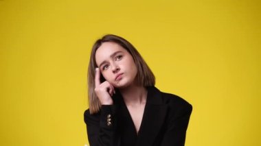 Bir kızın ellerini sarı arka planda gezdirerek bir şeyler planladığı 4K video. Duyguların kavramı.