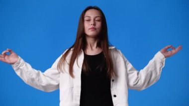 Mavi arka planda meditasyon yapan bir kızın 4K videosu. Duygu kavramı.