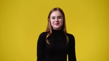 Sarı arka planda poz veren bir kızın 4K videosu. Duyguların kavramı.