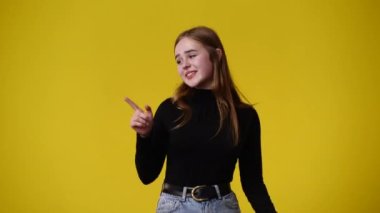 4k video of one girl pointing at right over yellow background. Concept of emotions.