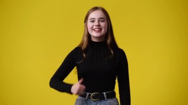 4k video of one girl showing thumbs up over yellow background. Concept of emotions.