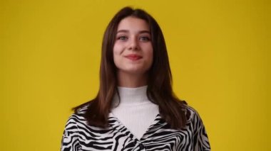 Sarı arka planda gülümseyen güzel bir kızın 4K videosu. Duyguların kavramı.