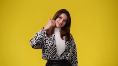 Kamerayı işaret eden ve sarı arka planda başparmağını gösteren 4K video. Duyguların kavramı.