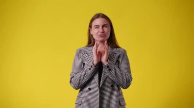 Sarı arka planda el çırpan heyecanlı kızın 4K videosu. El çırpma kavramı.